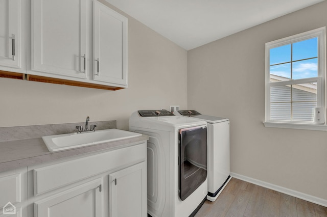 washroom featuring cabinets, sink, light hardwood / wood-style floors, and washing machine and clothes dryer