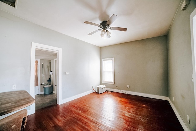 empty room featuring dark wood-style floors, baseboards, visible vents, and a ceiling fan