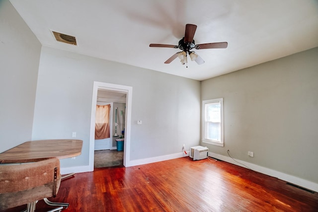 spare room featuring a ceiling fan, wood finished floors, visible vents, and baseboards