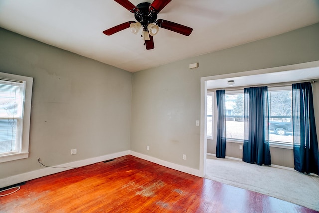 unfurnished room featuring a ceiling fan, visible vents, baseboards, and wood finished floors