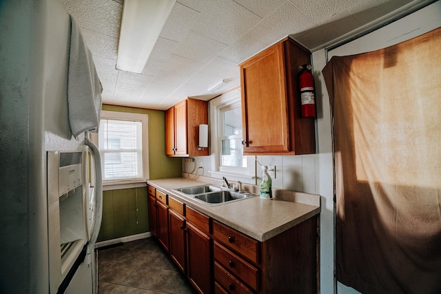 kitchen with white fridge with ice dispenser, a wealth of natural light, brown cabinets, and a sink