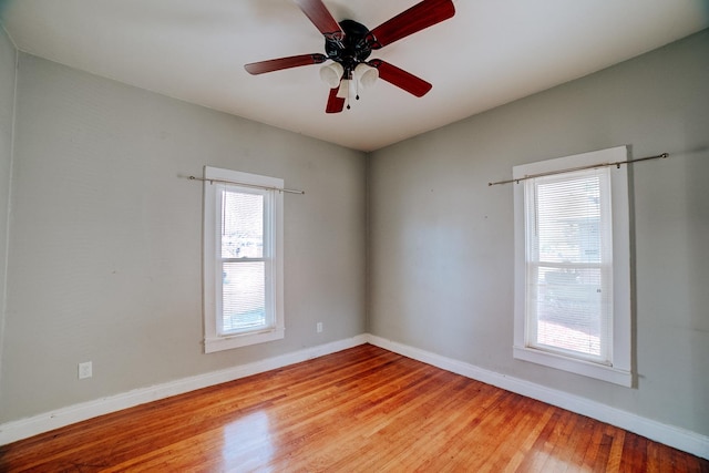 empty room featuring ceiling fan, light wood finished floors, and baseboards