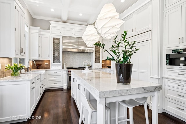 kitchen featuring tasteful backsplash, stainless steel range, a sink, beamed ceiling, and white cabinetry