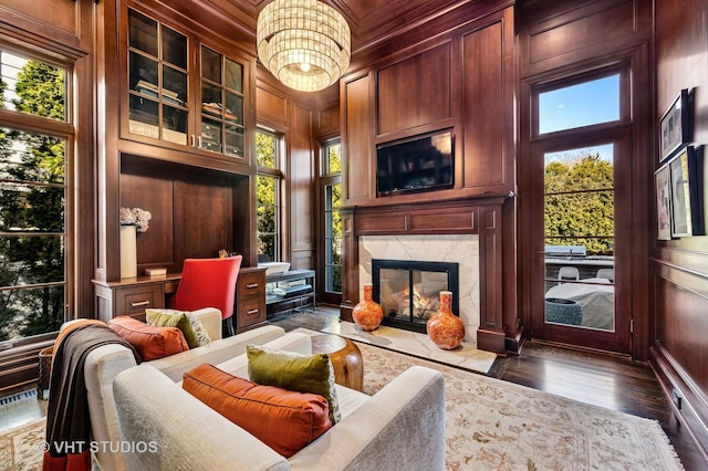 living area featuring a decorative wall, wood walls, a premium fireplace, and dark wood-style flooring