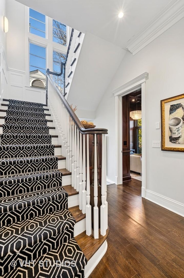 stairs featuring lofted ceiling, baseboards, ornamental molding, and wood finished floors