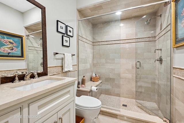 bathroom with a shower stall, vanity, toilet, wainscoting, and tile walls