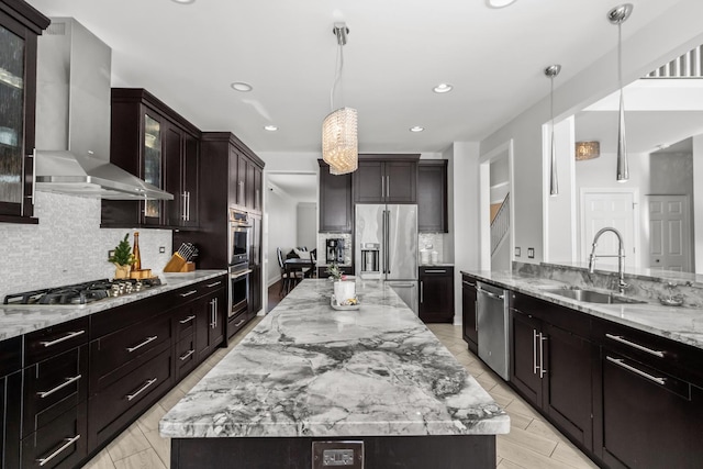 kitchen featuring pendant lighting, a spacious island, stainless steel appliances, glass insert cabinets, and wall chimney exhaust hood