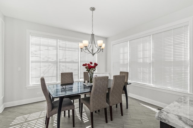 dining room featuring wood tiled floor, baseboards, and an inviting chandelier