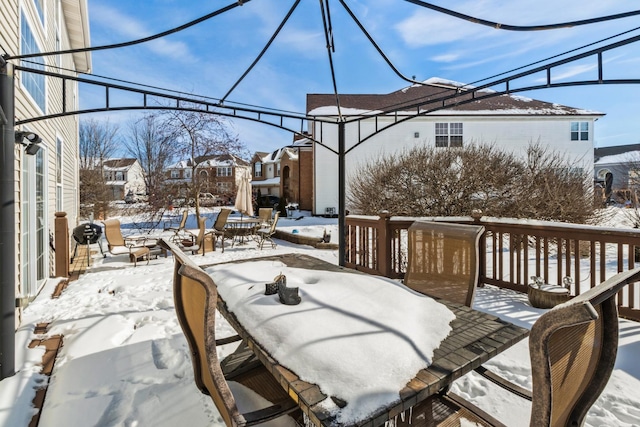 snow covered patio featuring a residential view and a wooden deck