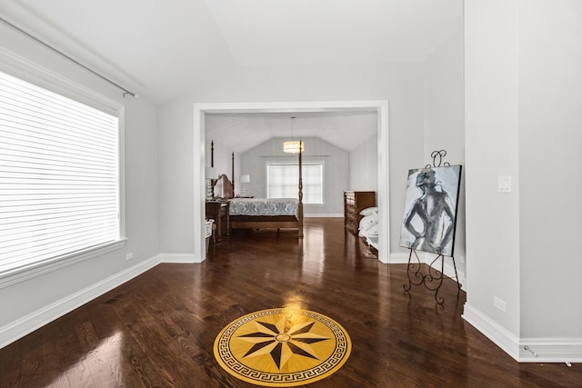 unfurnished bedroom with lofted ceiling, wood finished floors, and baseboards