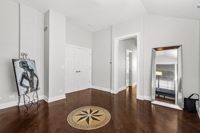 interior space with baseboards, vaulted ceiling, visible vents, and dark wood finished floors