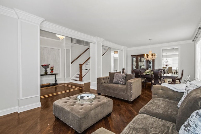 living room featuring dark wood finished floors, stairway, ornamental molding, ornate columns, and a chandelier