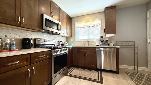 kitchen with appliances with stainless steel finishes, decorative backsplash, sink, and dark brown cabinetry