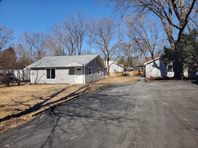 view of side of property with driveway and roof with shingles