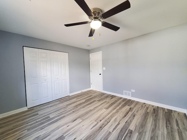 unfurnished bedroom with baseboards, a closet, visible vents, and wood finished floors