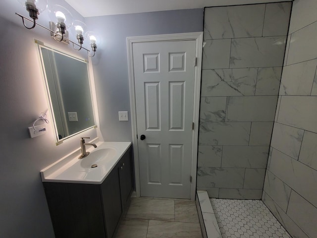 full bath with marble finish floor, tiled shower, a notable chandelier, and vanity