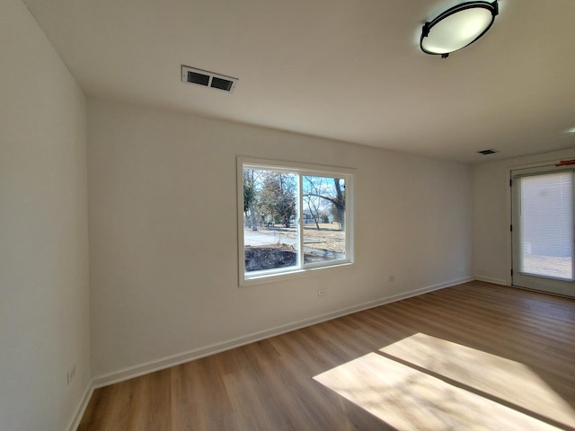 unfurnished room with visible vents, baseboards, and wood finished floors