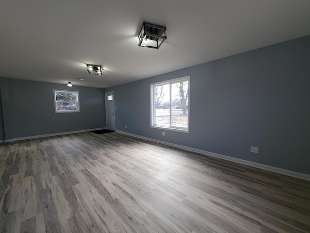 spare room featuring a wealth of natural light, baseboards, and wood finished floors