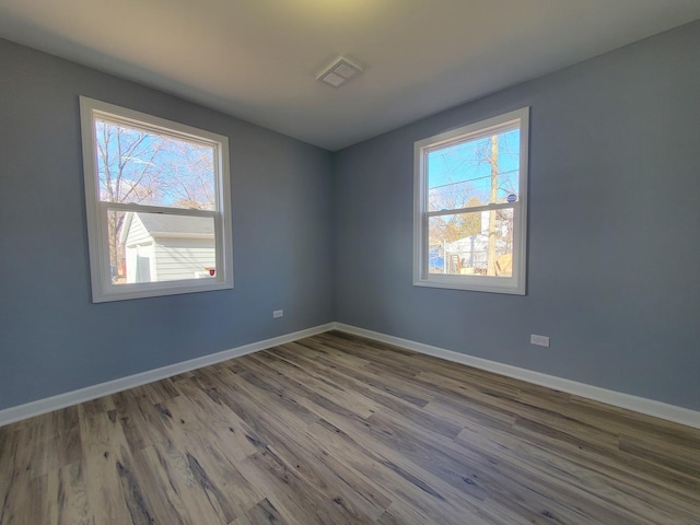 spare room with visible vents, baseboards, and wood finished floors