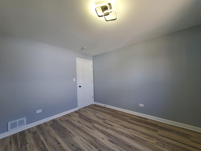 spare room featuring dark wood-type flooring, visible vents, and baseboards