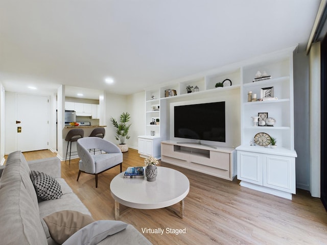 living room with light hardwood / wood-style flooring and built in shelves