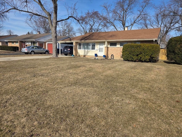 ranch-style home featuring a chimney, driveway, a front lawn, a carport, and brick siding