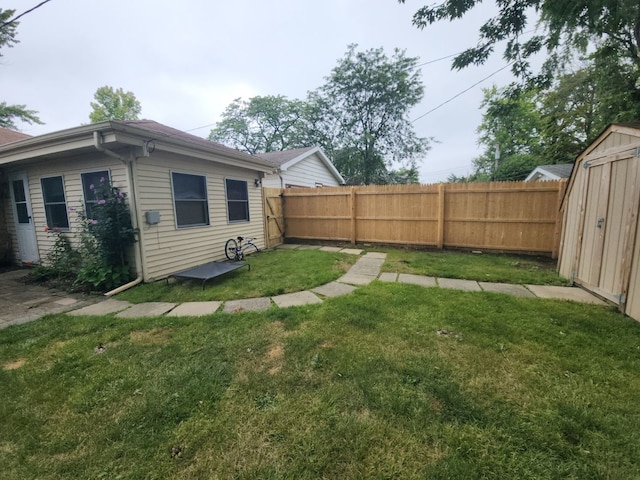 view of yard featuring a storage shed, an outdoor structure, and a fenced backyard