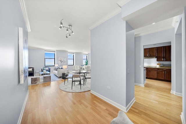 hall featuring light wood finished floors, ornamental molding, and baseboards