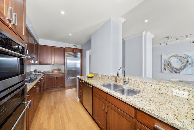 kitchen featuring light wood finished floors, visible vents, appliances with stainless steel finishes, light stone counters, and a sink