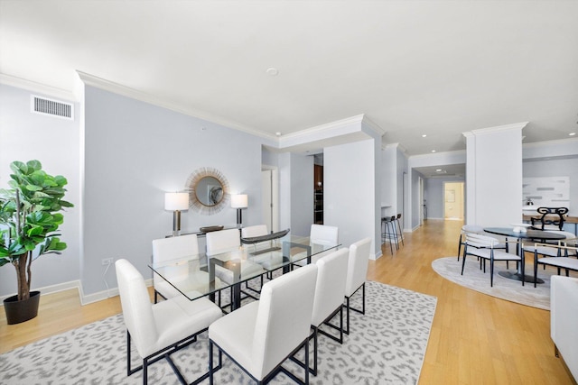 dining space with light wood-type flooring, baseboards, visible vents, and ornamental molding