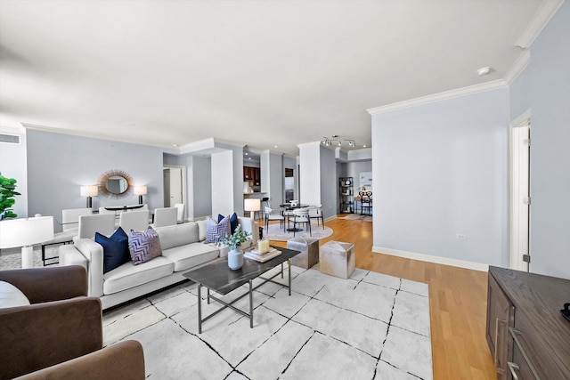 living room with light wood-style flooring, visible vents, ornamental molding, and baseboards