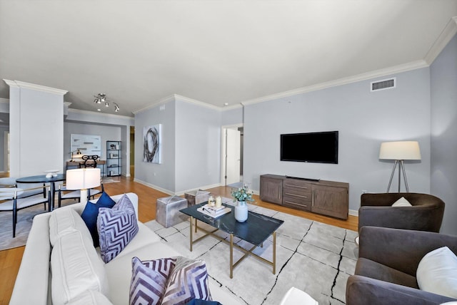 living area with ornamental molding, baseboards, visible vents, and light wood finished floors