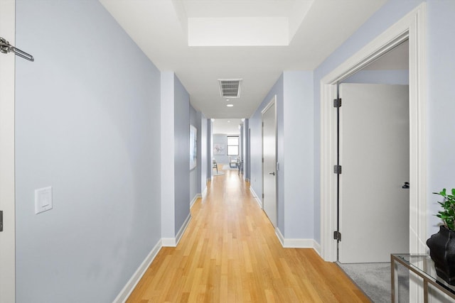 hall featuring light wood-type flooring, visible vents, and baseboards