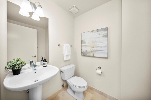 bathroom featuring baseboards, visible vents, toilet, tile patterned flooring, and a sink