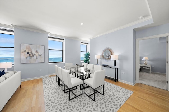 dining space featuring baseboards, light wood-type flooring, and crown molding