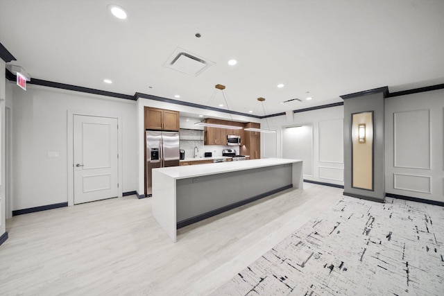 kitchen with light wood-style flooring, stainless steel appliances, crown molding, light countertops, and a decorative wall