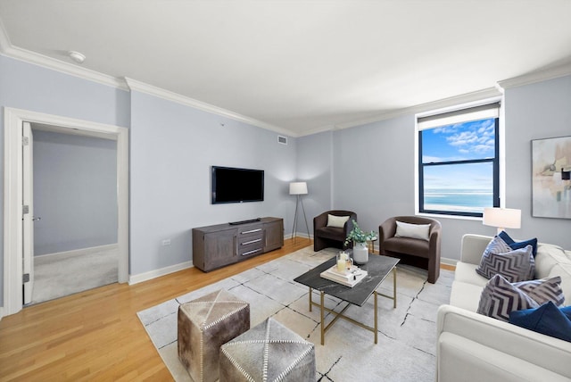 living room with ornamental molding, light wood-type flooring, visible vents, and baseboards