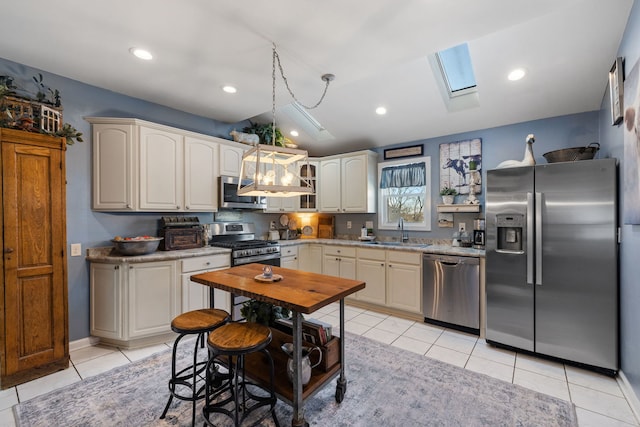 kitchen with stainless steel appliances, a skylight, a sink, light countertops, and decorative light fixtures