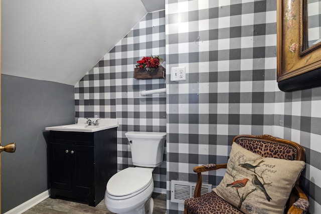 half bath with visible vents, toilet, vaulted ceiling, vanity, and baseboards