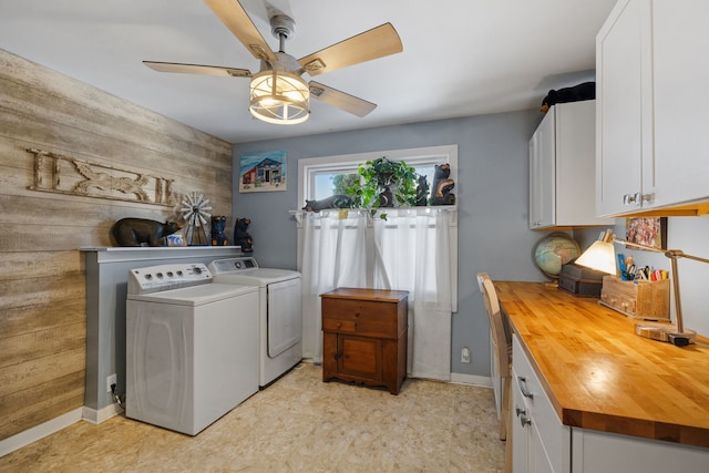 laundry area with cabinet space, wooden walls, baseboards, a ceiling fan, and separate washer and dryer