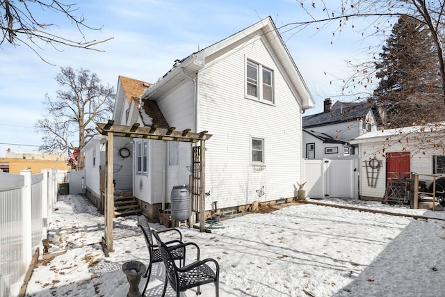 snow covered back of property with a fenced backyard