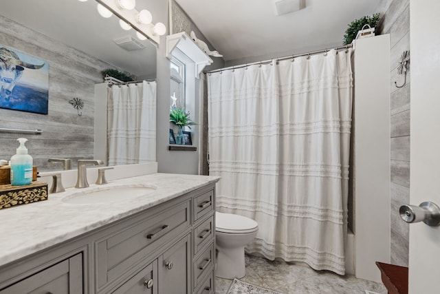 full bath with visible vents, wood walls, vanity, and toilet