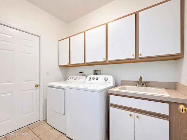 washroom featuring cabinet space, washer and dryer, a sink, and light tile patterned flooring