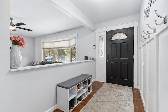 foyer featuring wood finished floors, beam ceiling, and baseboards