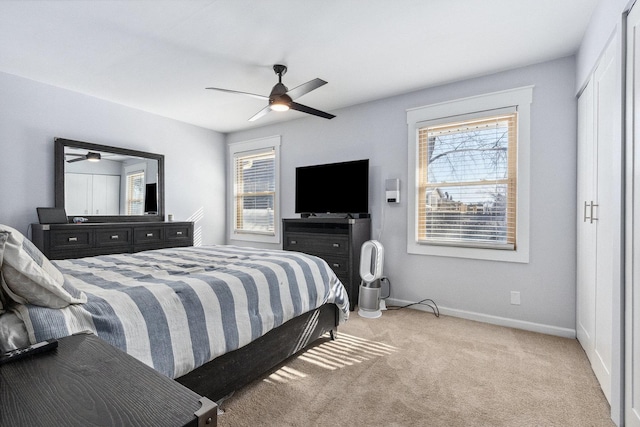 bedroom with multiple windows, baseboards, a ceiling fan, and light colored carpet