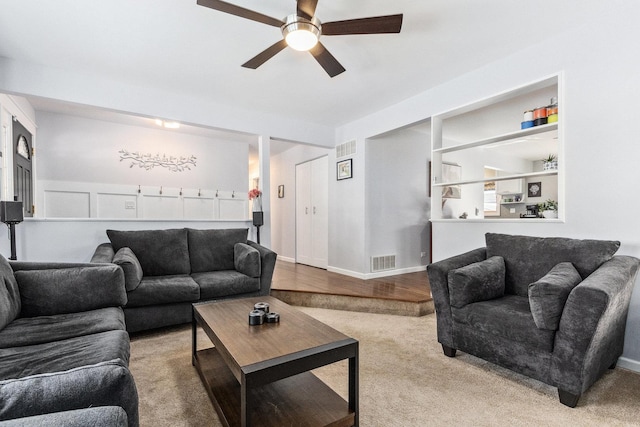 living area featuring baseboards, visible vents, and a ceiling fan