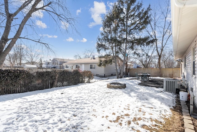 yard covered in snow featuring an outdoor fire pit, a fenced backyard, and central AC unit