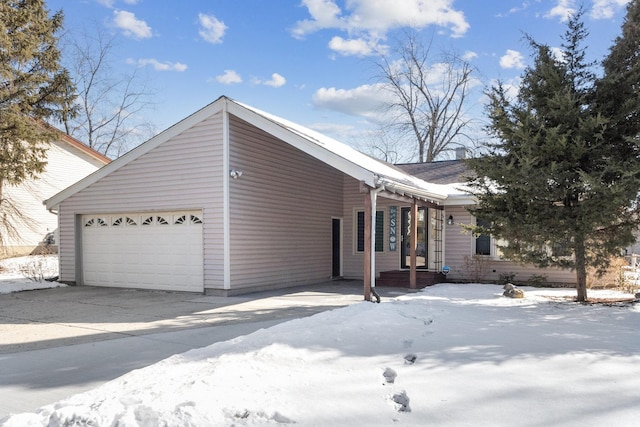 snow covered property with driveway and an attached garage