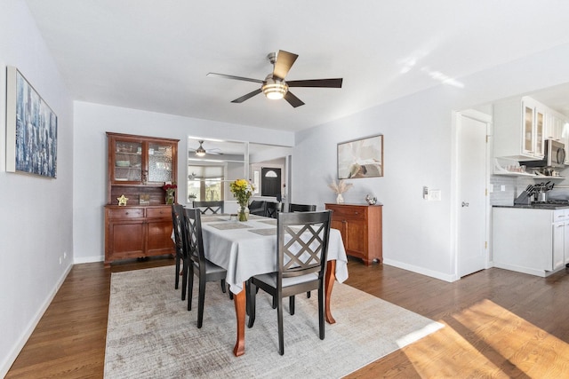 dining room featuring dark wood-style floors, ceiling fan, and baseboards