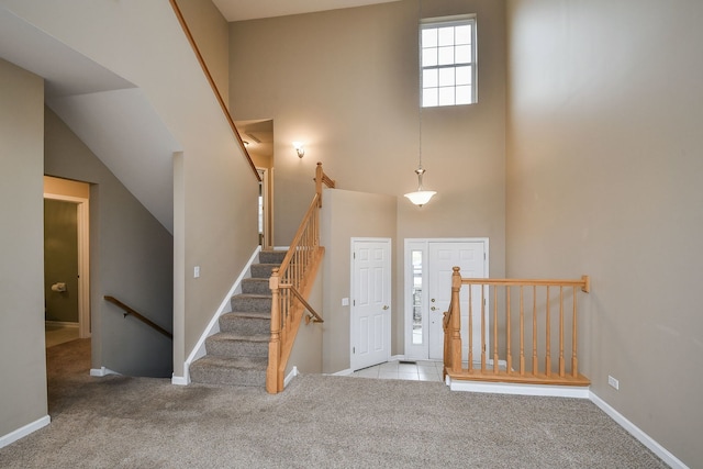 foyer featuring a towering ceiling, baseboards, and carpet flooring